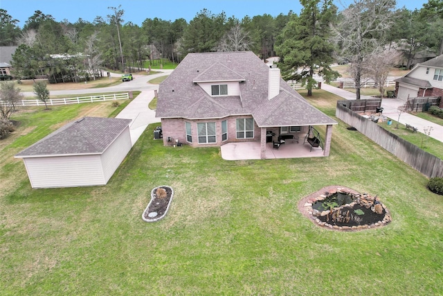 back of house with a lawn, a fenced backyard, a shingled roof, brick siding, and a patio area