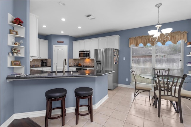 kitchen with a notable chandelier, a sink, white cabinetry, appliances with stainless steel finishes, and a peninsula