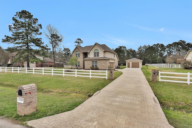 view of front of property with fence, a front lawn, an outdoor structure, a rural view, and a detached garage