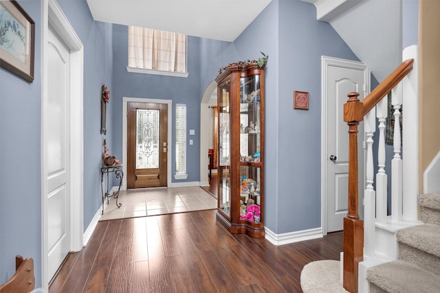 entrance foyer featuring stairs, wood finished floors, arched walkways, and baseboards