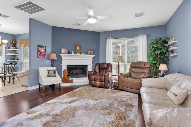 living room with visible vents, a fireplace with raised hearth, and wood finished floors