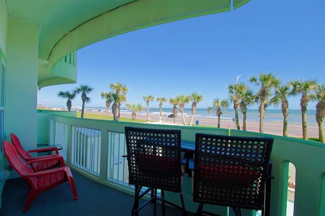 balcony with a water view and a view of the beach