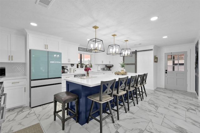 kitchen featuring a barn door, marble finish floor, visible vents, and freestanding refrigerator