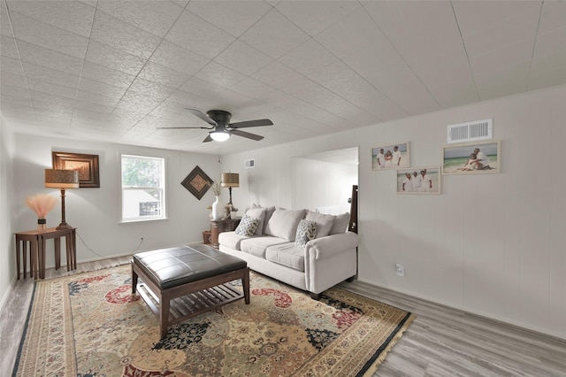 living room featuring ceiling fan, visible vents, and wood finished floors