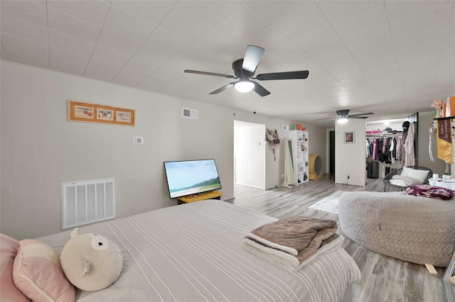 bedroom with a ceiling fan, wood finished floors, and visible vents