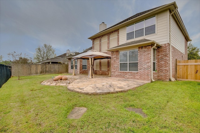 rear view of house with a fenced backyard, a chimney, a yard, a patio area, and brick siding