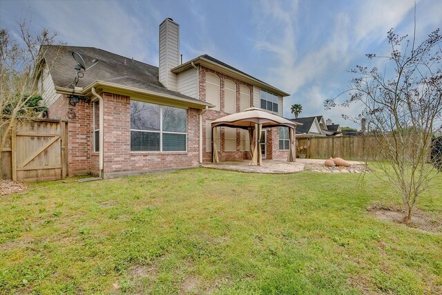 back of property featuring a patio, a chimney, fence, a yard, and brick siding