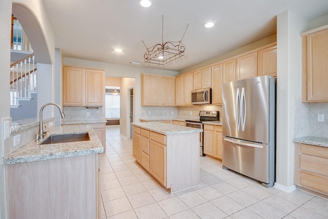 kitchen with light tile patterned floors, stainless steel appliances, a sink, and light brown cabinetry