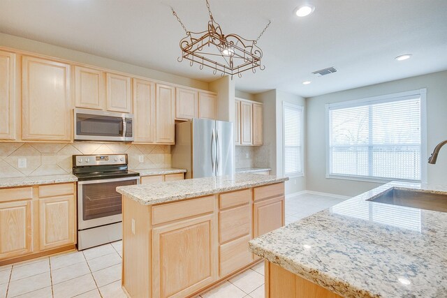 kitchen with appliances with stainless steel finishes, visible vents, a sink, and light brown cabinetry