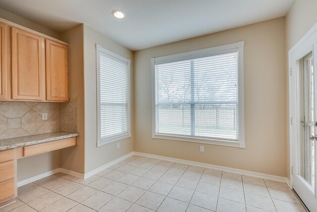 unfurnished dining area featuring built in study area, baseboards, and light tile patterned floors