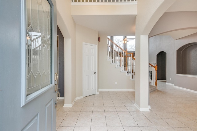 foyer featuring light tile patterned floors, baseboards, and stairway