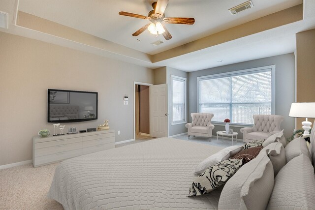 carpeted bedroom with a ceiling fan, a raised ceiling, visible vents, and baseboards