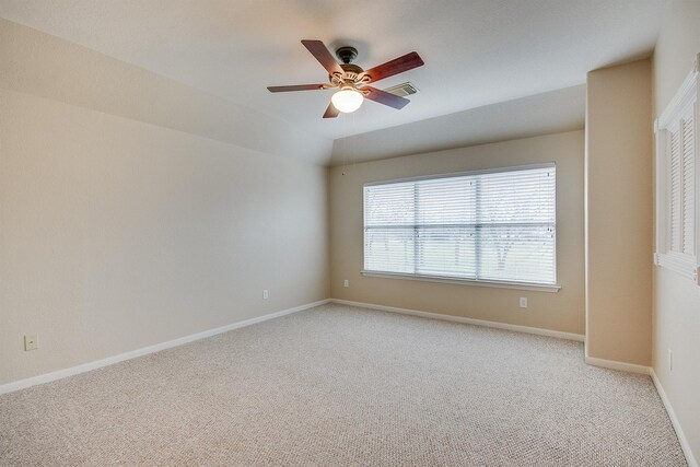 spare room featuring lofted ceiling, light colored carpet, a ceiling fan, visible vents, and baseboards