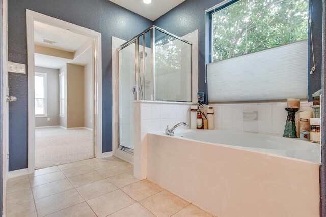 bathroom with a stall shower, tile patterned flooring, a garden tub, and a textured wall