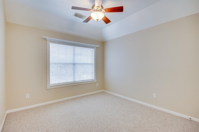 unfurnished room featuring carpet flooring, a ceiling fan, visible vents, vaulted ceiling, and baseboards