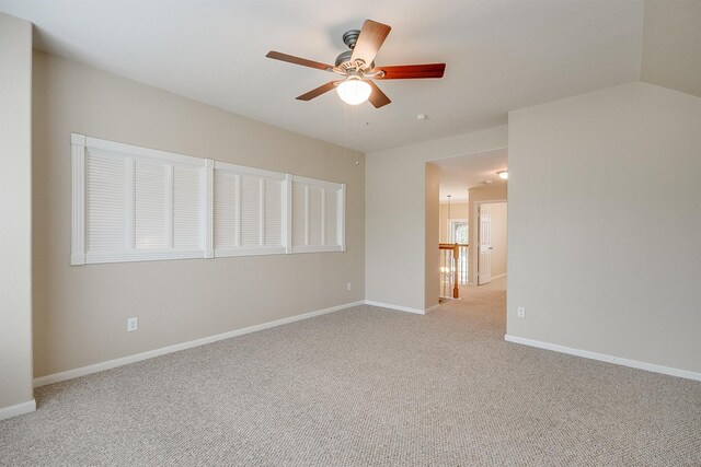 carpeted spare room with lofted ceiling, baseboards, and a ceiling fan