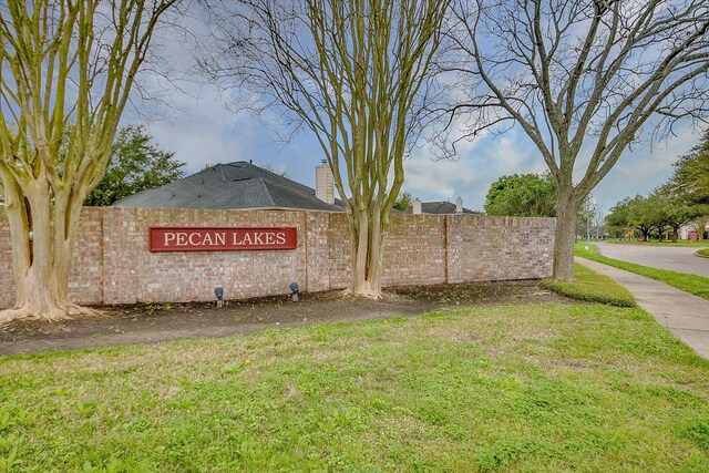 community / neighborhood sign with a lawn and fence