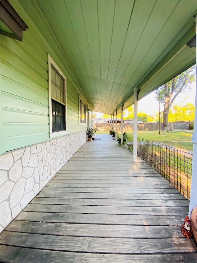 wooden terrace with covered porch and a lawn