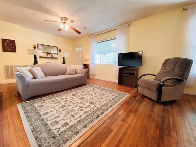 living area featuring visible vents, a textured ceiling, and hardwood / wood-style flooring