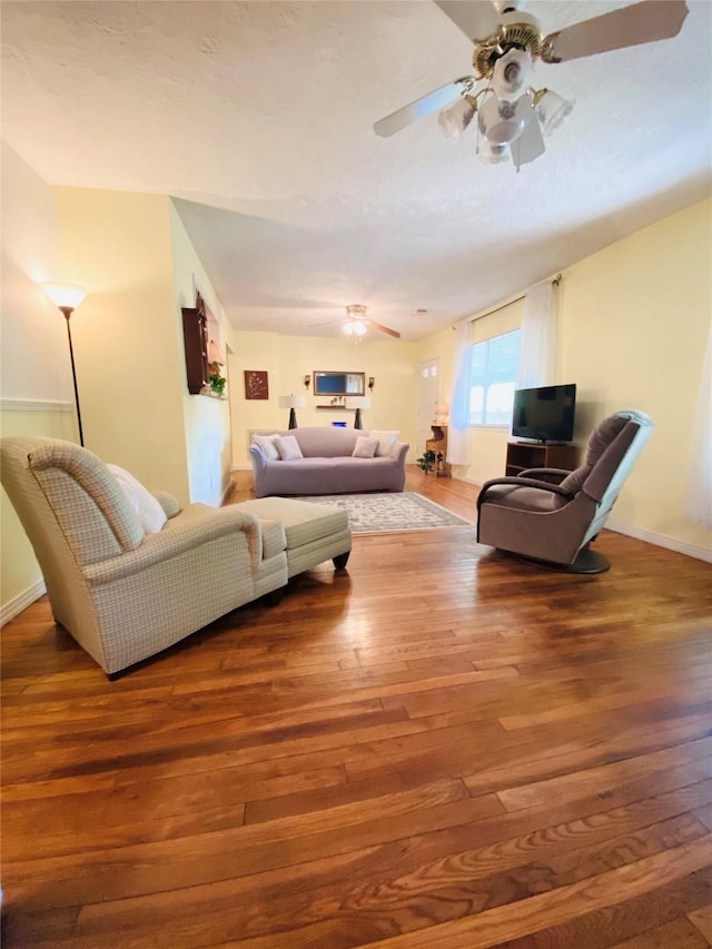 living room with hardwood / wood-style floors, a ceiling fan, and baseboards