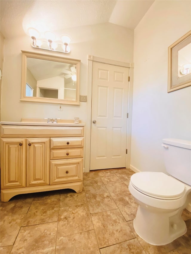 bathroom with lofted ceiling, tile patterned flooring, vanity, and toilet