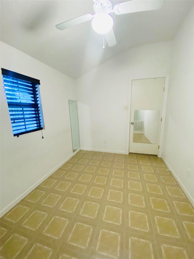 spare room with ceiling fan, lofted ceiling, and baseboards