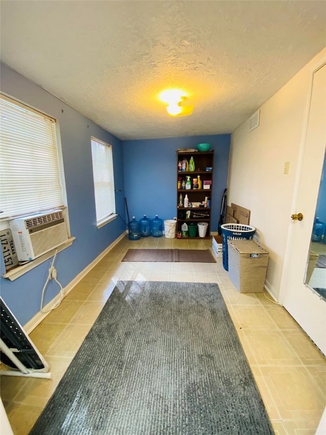 interior space featuring baseboards, tile patterned flooring, visible vents, and a textured ceiling