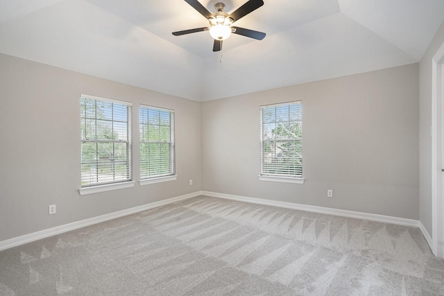 empty room with baseboards, vaulted ceiling, a ceiling fan, and light colored carpet