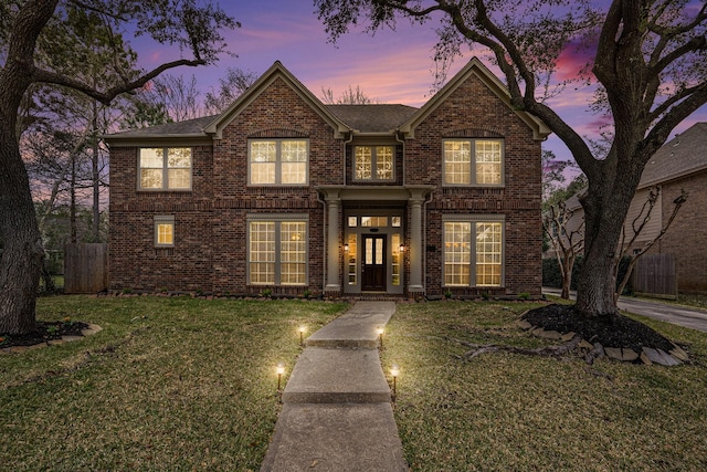 traditional home with a front lawn, french doors, and brick siding