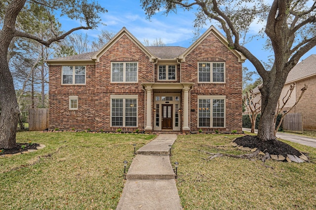 traditional home with a front yard, brick siding, and fence