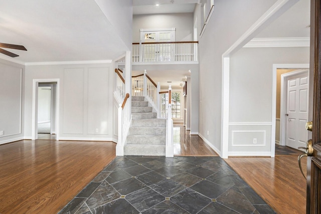 foyer entrance featuring ceiling fan, ornamental molding, wood finished floors, and a decorative wall