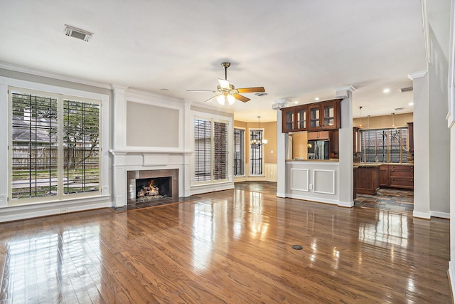 unfurnished living room with visible vents, dark wood finished floors, a tiled fireplace, and ceiling fan with notable chandelier