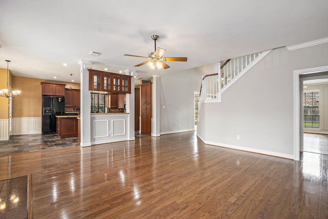 unfurnished living room featuring dark wood-style floors, crown molding, ceiling fan with notable chandelier, and baseboards