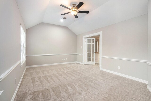 carpeted spare room with lofted ceiling, ceiling fan, visible vents, and baseboards