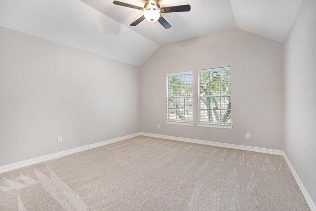 spare room with light carpet, ceiling fan, lofted ceiling, and baseboards