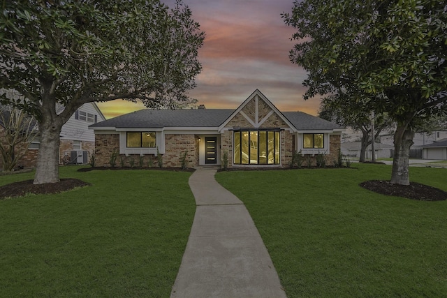 view of front facade with brick siding, a front yard, and cooling unit