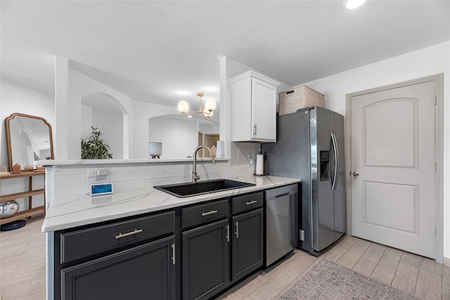 kitchen featuring wood finish floors, stainless steel appliances, tasteful backsplash, white cabinets, and a sink