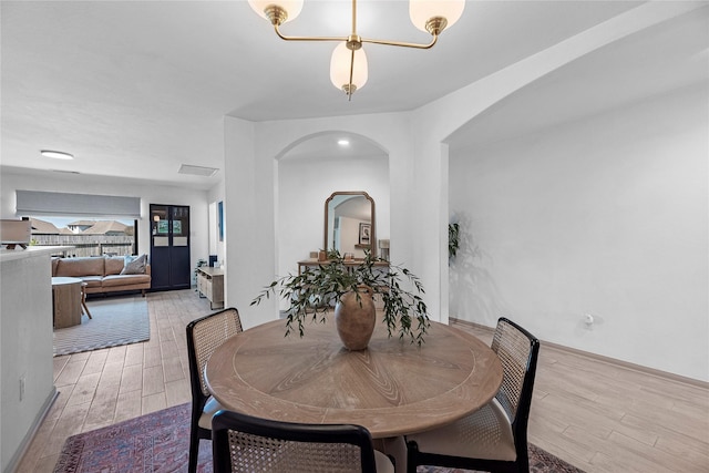 dining room featuring arched walkways, visible vents, and light wood-style flooring