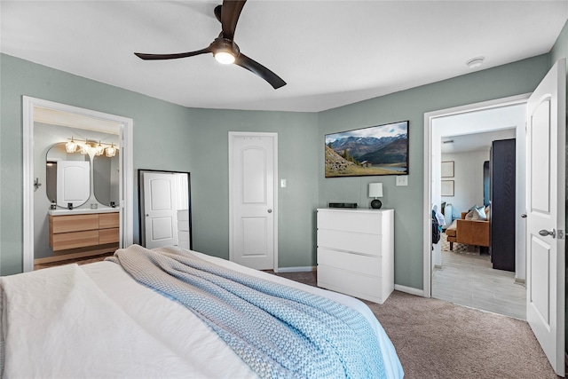 carpeted bedroom featuring ensuite bathroom, a ceiling fan, and baseboards