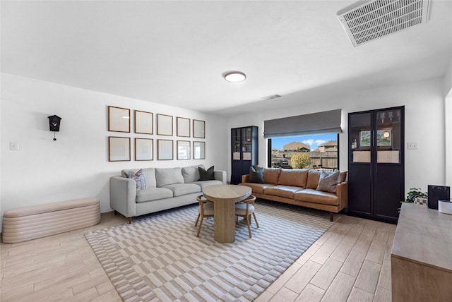 living area with visible vents and light wood-style floors