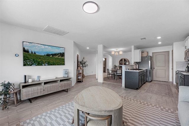 living area featuring light wood-type flooring, arched walkways, visible vents, and recessed lighting