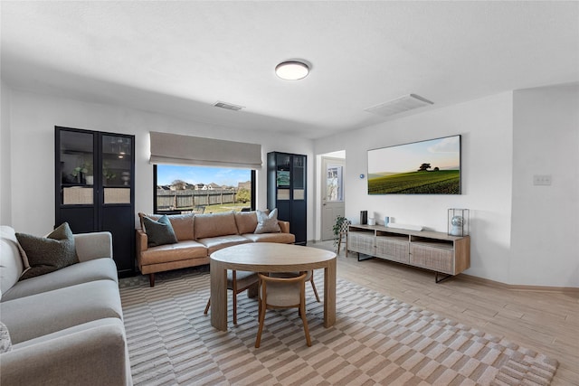 living room with baseboards, visible vents, and light wood-style floors