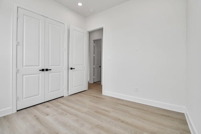 unfurnished bedroom with light wood-type flooring, a closet, baseboards, and recessed lighting