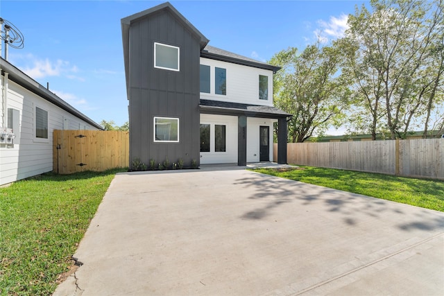 view of front facade with board and batten siding, a front yard, and fence