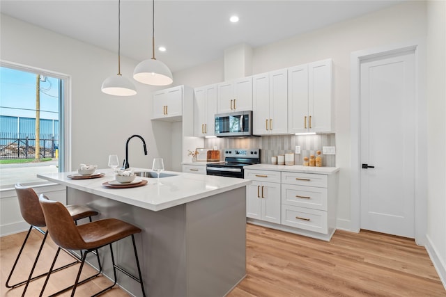 kitchen featuring stainless steel appliances, a breakfast bar, a sink, decorative backsplash, and light wood finished floors