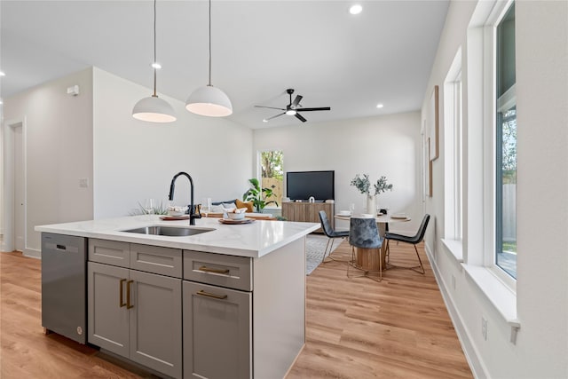 kitchen with dishwasher, a sink, light wood-style flooring, and gray cabinetry