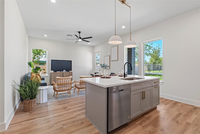 kitchen featuring gray cabinets, light countertops, stainless steel dishwasher, light wood-style floors, and a sink