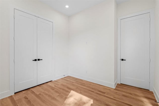 unfurnished bedroom with baseboards, a closet, recessed lighting, and light wood-style floors