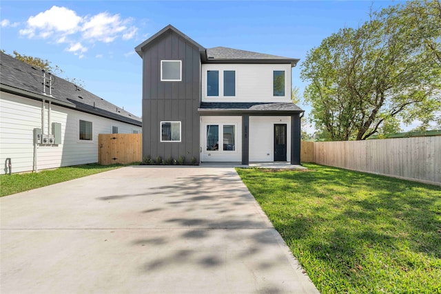 view of front of home with board and batten siding, a front yard, fence, and a patio