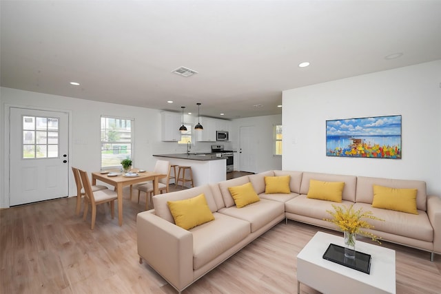 living area with light wood-style floors, visible vents, and recessed lighting